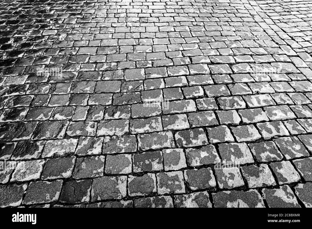 Top view on paving wet stone road after rain. Old pavement of granite