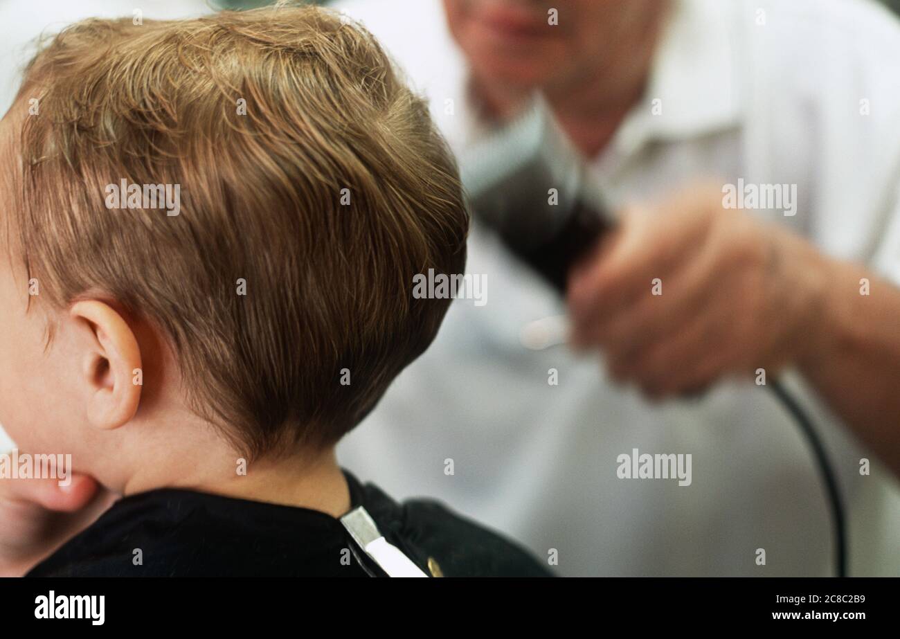 Boy having hair shaved in barbers Stock Photo