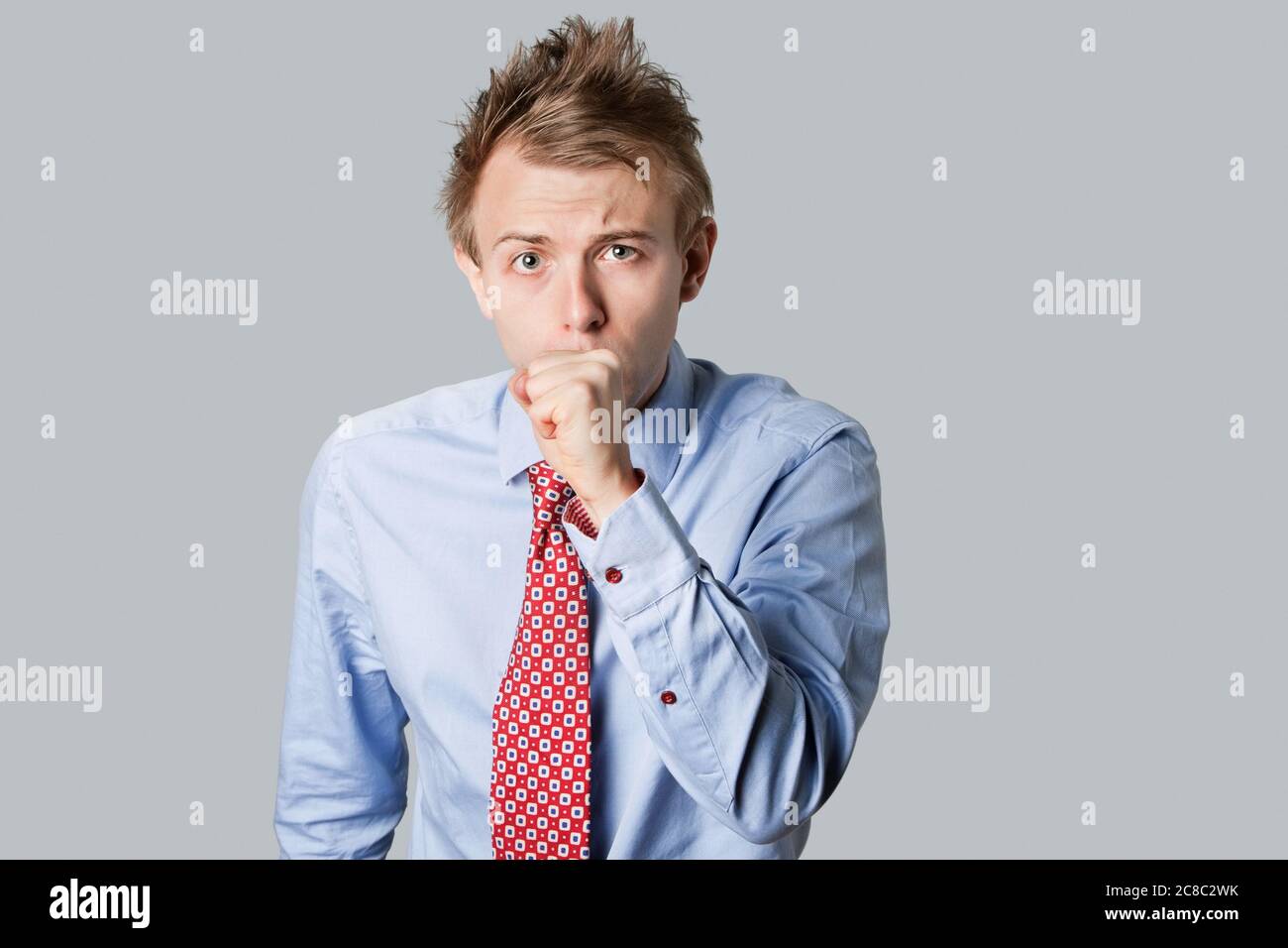 Young businessman coughing and looking into camera Stock Photo