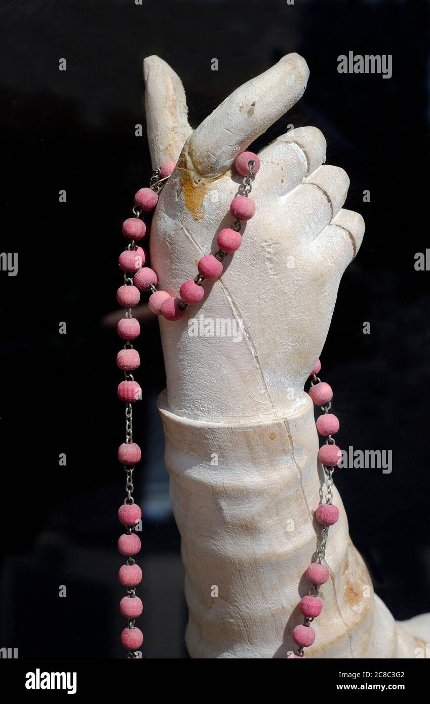pink worry beads held in hand on wooden female sculpture, little walsingham, norfolk, england Stock Photo