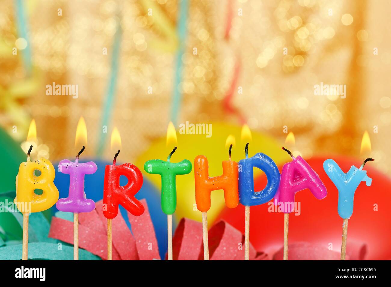 lit birthday candles in front of party items Stock Photo Alamy