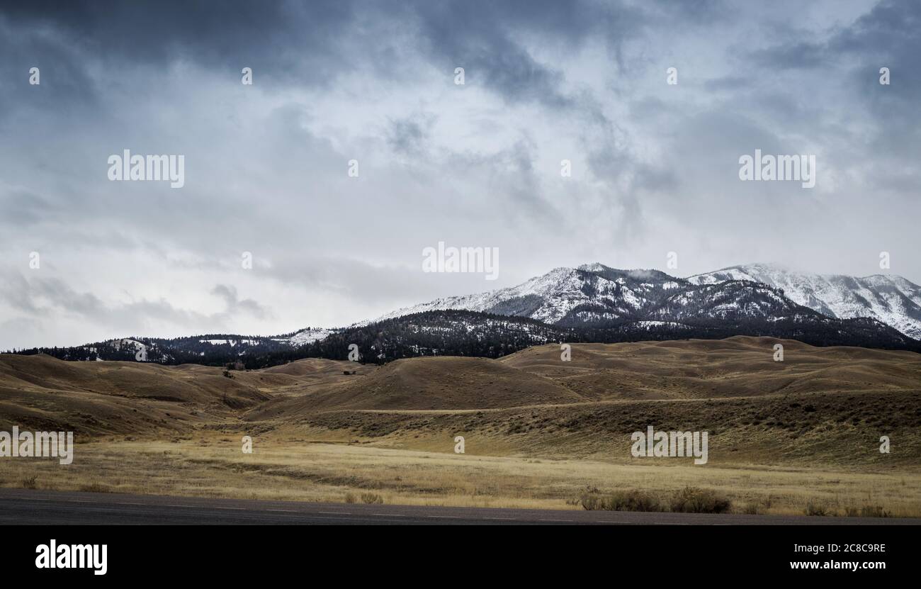 Schnee bedeckte Berge vor grünen Hügeln am Rande des Yellowstone Nationalparks am Nord Eingang in Gardiner, Montana Stock Photo