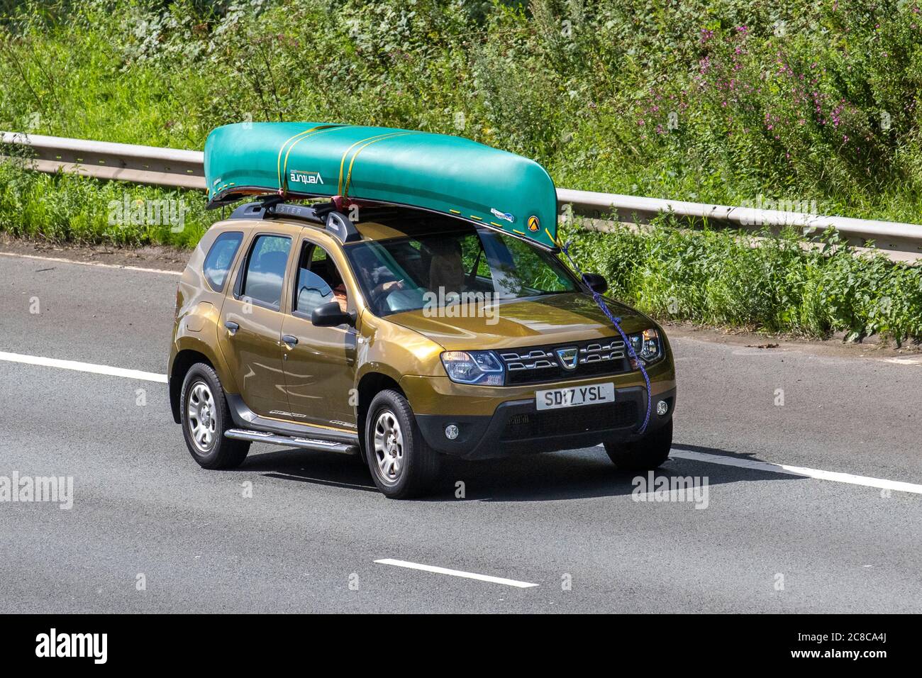 2017 bronze green Dacia Duster Ambiance DCI 4X2 1461cc diesel SUV carrying Venture canadian canoe; Vehicular traffic moving vehicles, cars driving vehicle on UK roads, motors, motoring on the M6 motorway highway network. Stock Photo
