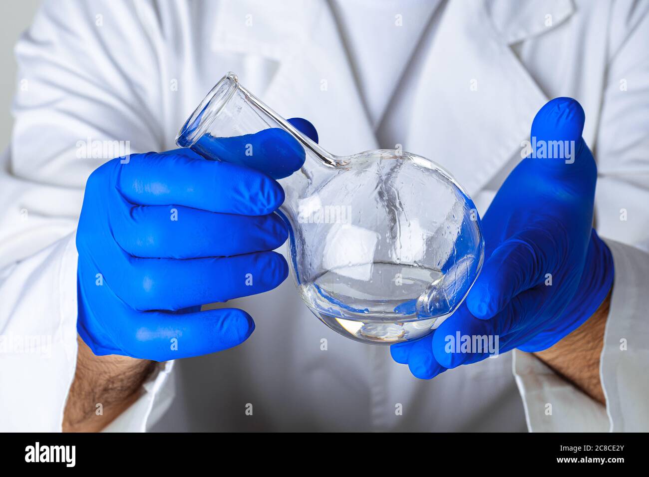 Scientist hands holding some liquid in a glassware in laboratory for