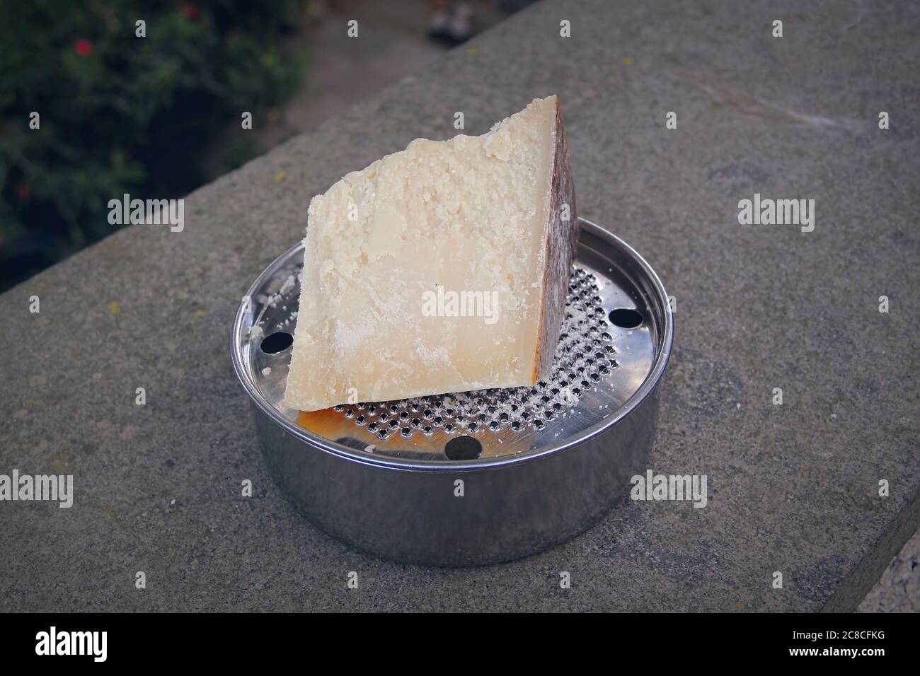 https://c8.alamy.com/comp/2C8CFKG/a-chunk-of-parmesan-cheese-on-a-typical-italian-grater-called-ratta-2C8CFKG.jpg