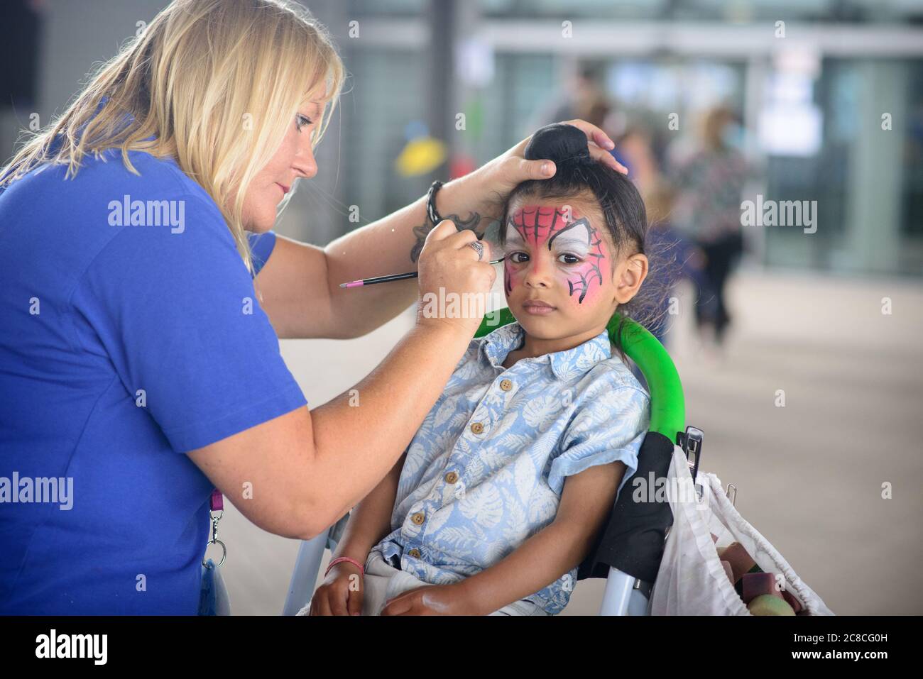 Face painting children at a family fun day. Face paint fun and many other family friendly activities outdoors on a cloudy summer day. Stock Photo