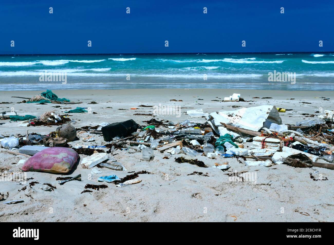 Plastic bottles and other rubbish thrown on the sandy seashore, trash on the sea beach. ecological problem. Environmental pollution. Dirty sandy beach Stock Photo