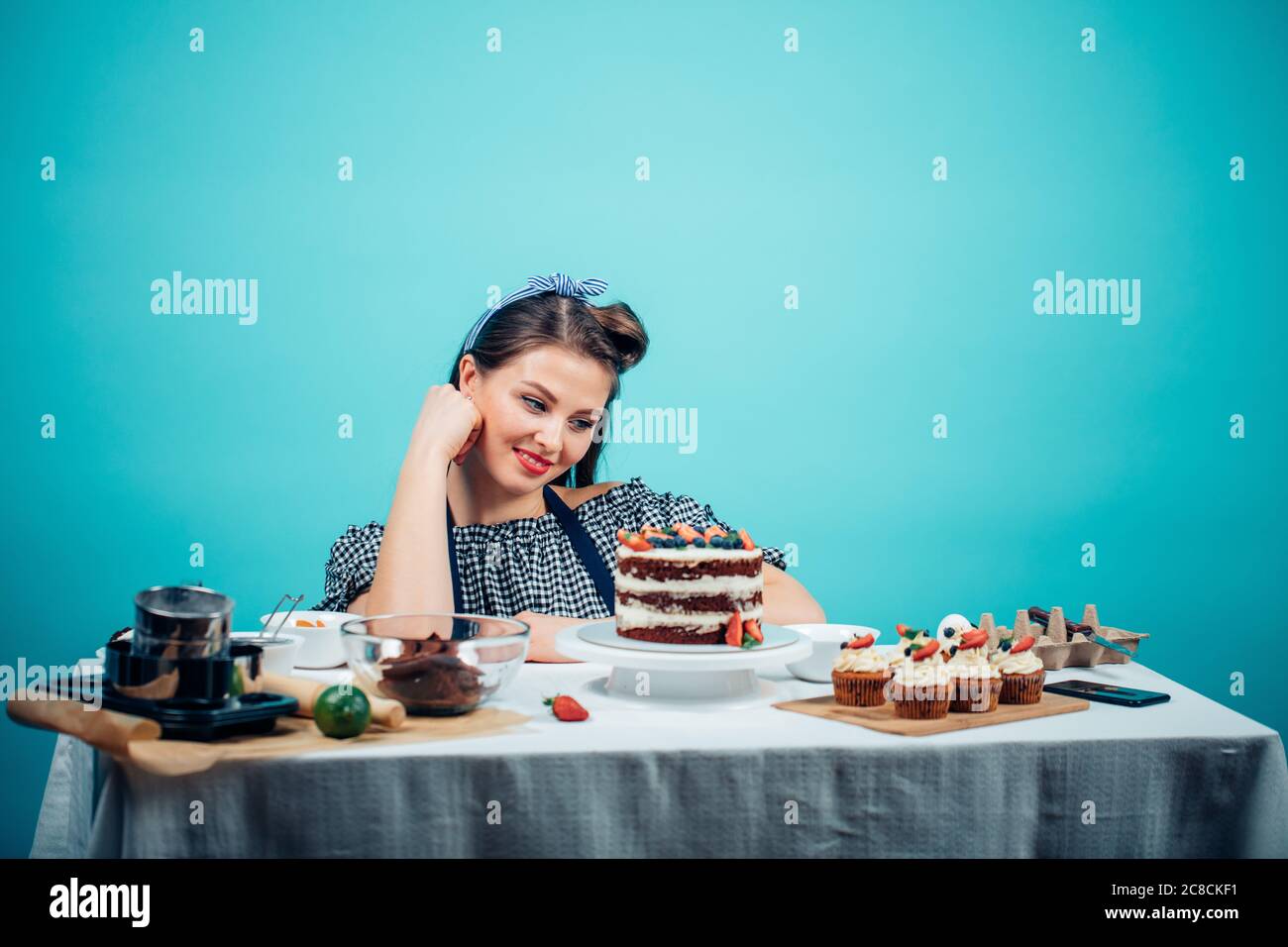 Young caucasian fashionable woman looking at delcious cake, eager to eat it. Stock Photo