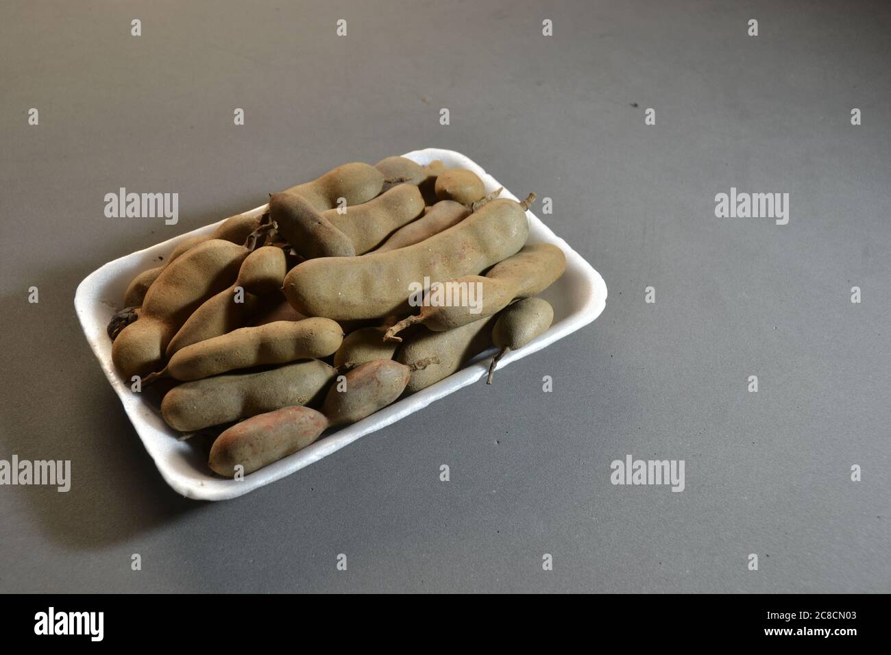 Tamarindo fruit, with plastic packaging, sold in supermarkets in a photo with a black background, with copy space. Brazil, South America Stock Photo