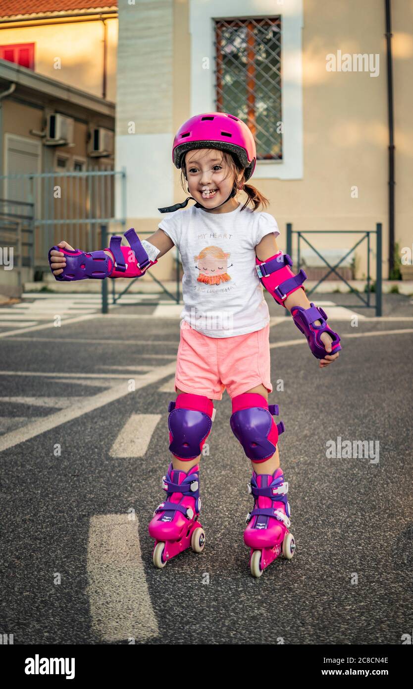 A little girl (child) learns to rollerblade on the street in the city
