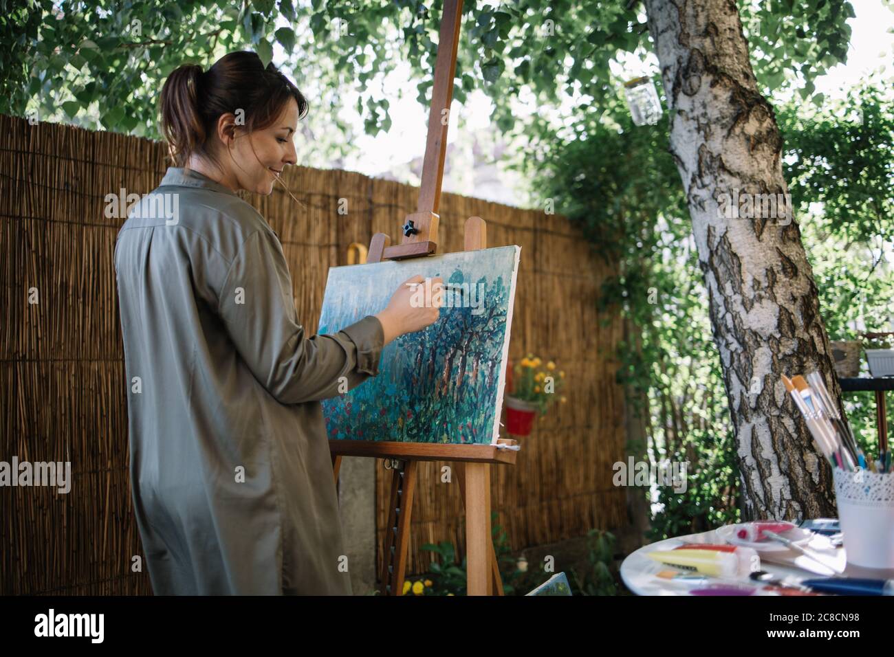 Happy female artist painting in nature using paint brush Stock Photo