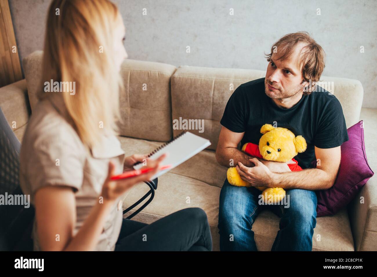 Female psychologist provides psychological assistance to an infantile adult man with a midlife crisis Stock Photo