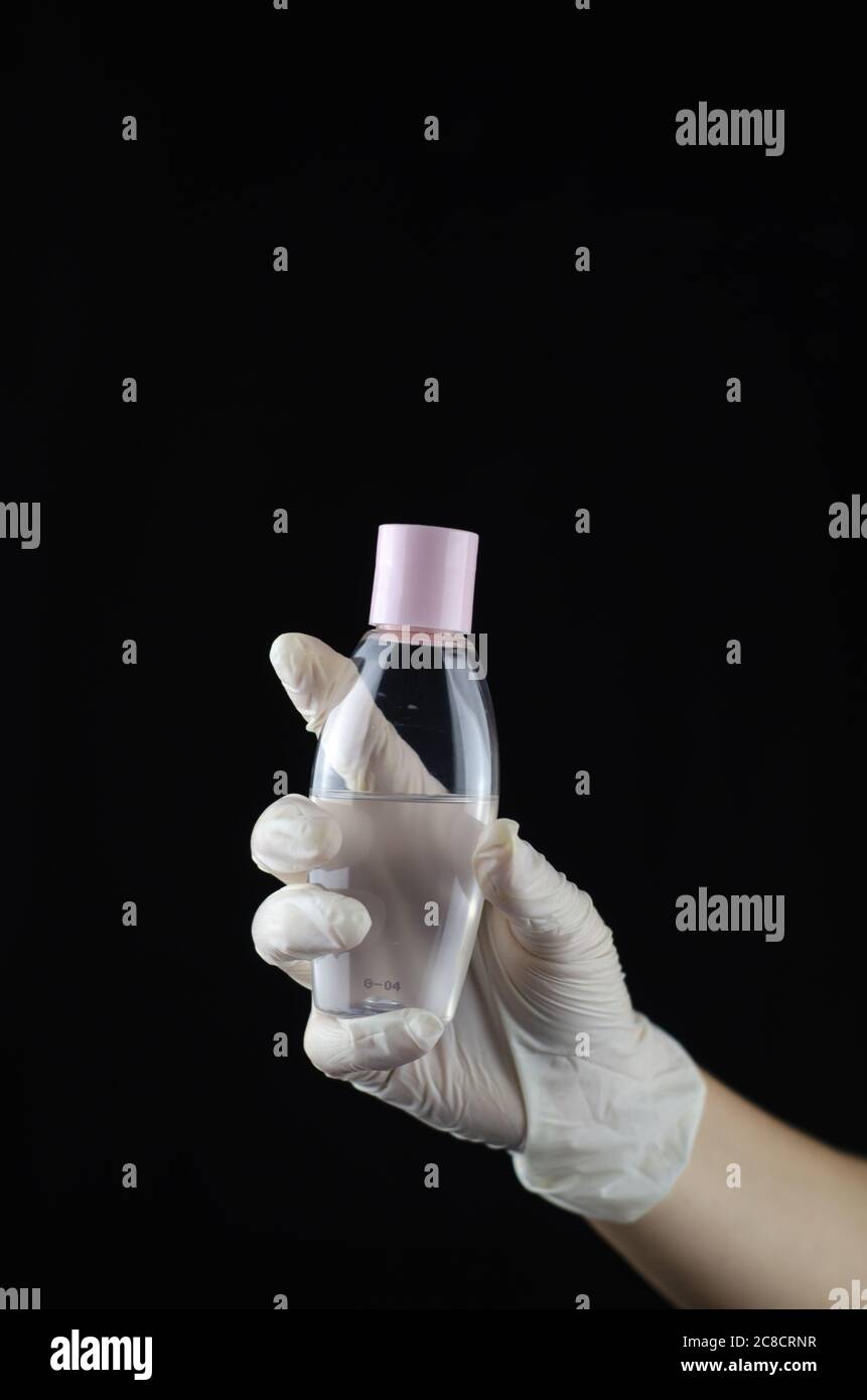 Human hand with rubber glove holding a plastic container of hand ...