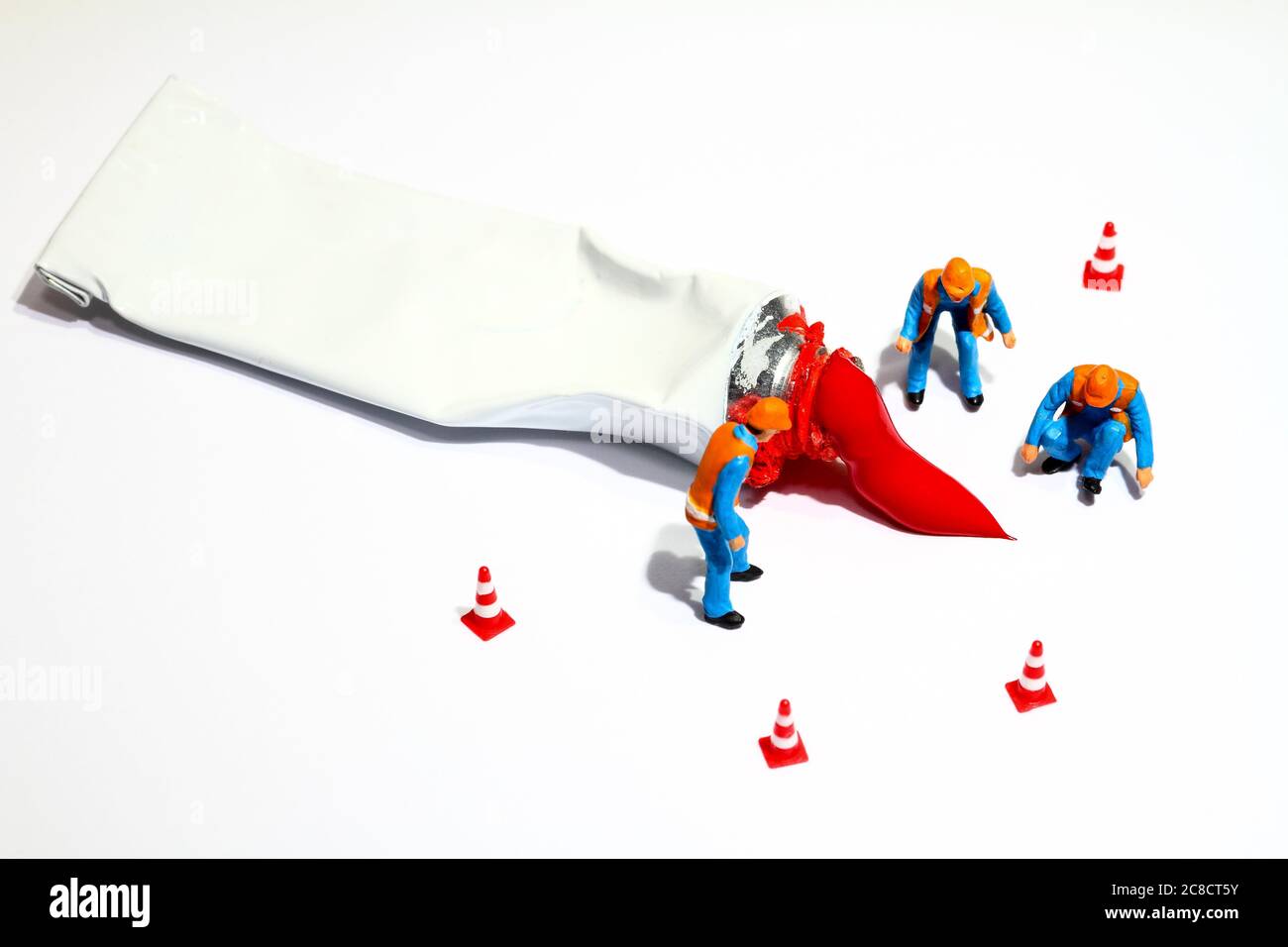 Miniature figure people investigating an artists red paint tube spillage Stock Photo
