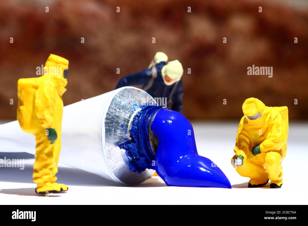 Miniature figure people wearing hazmat suits investigating a paint spill from an artists tube of acrylic paint Stock Photo