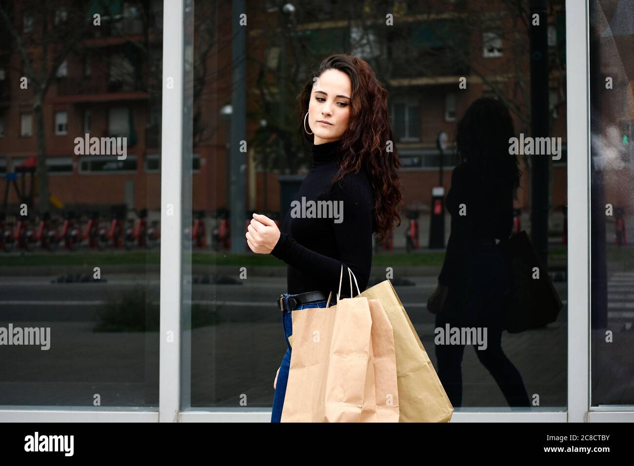 Fashion portrait woman with shopping bags wearing black while walking in the street Stock Photo