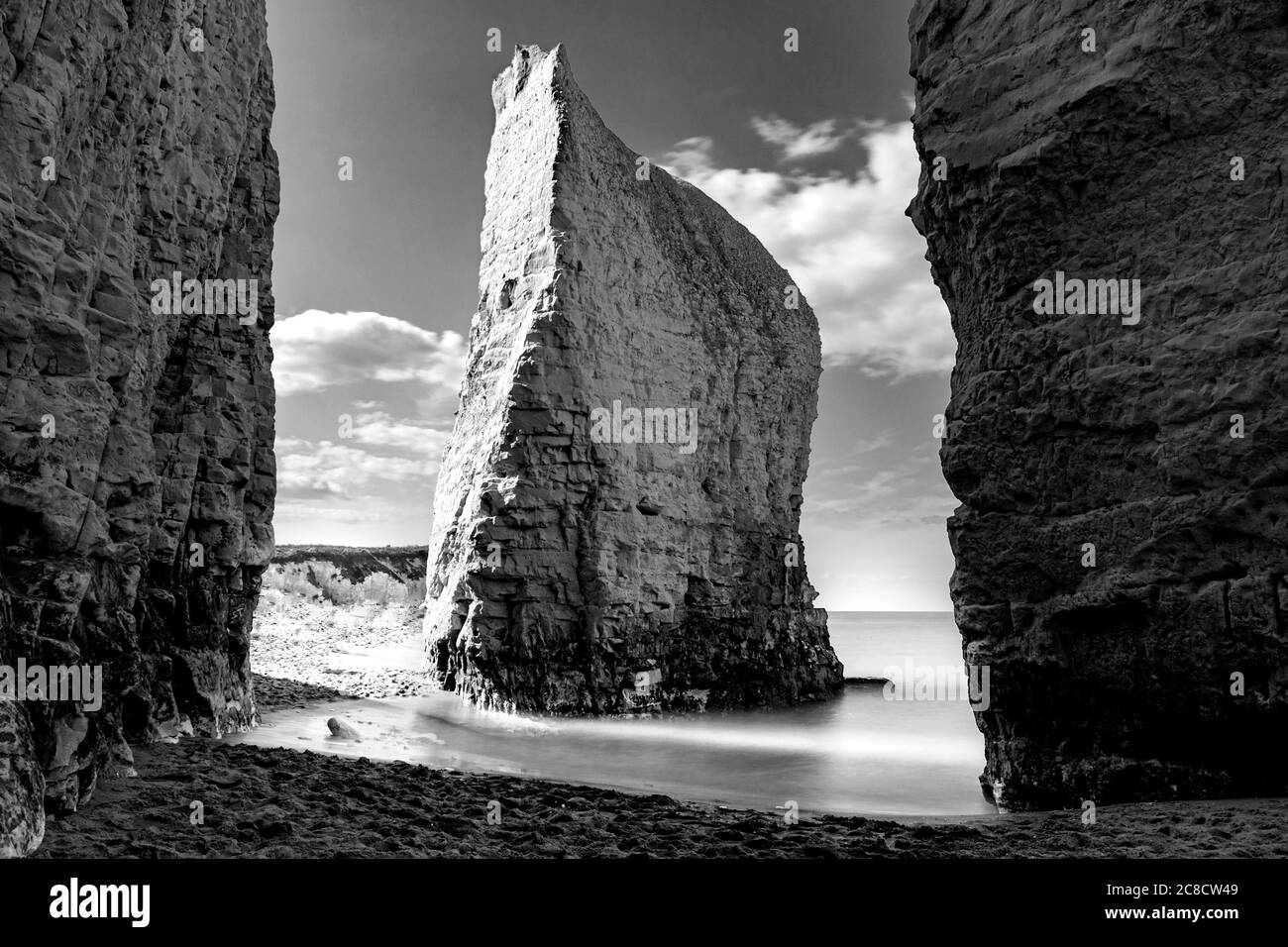 Dreamy tranquility concept with atmospheric monochrome photograph of iconic chalk steep cliff and long exposure of wave flow creating silky fine mist Stock Photo