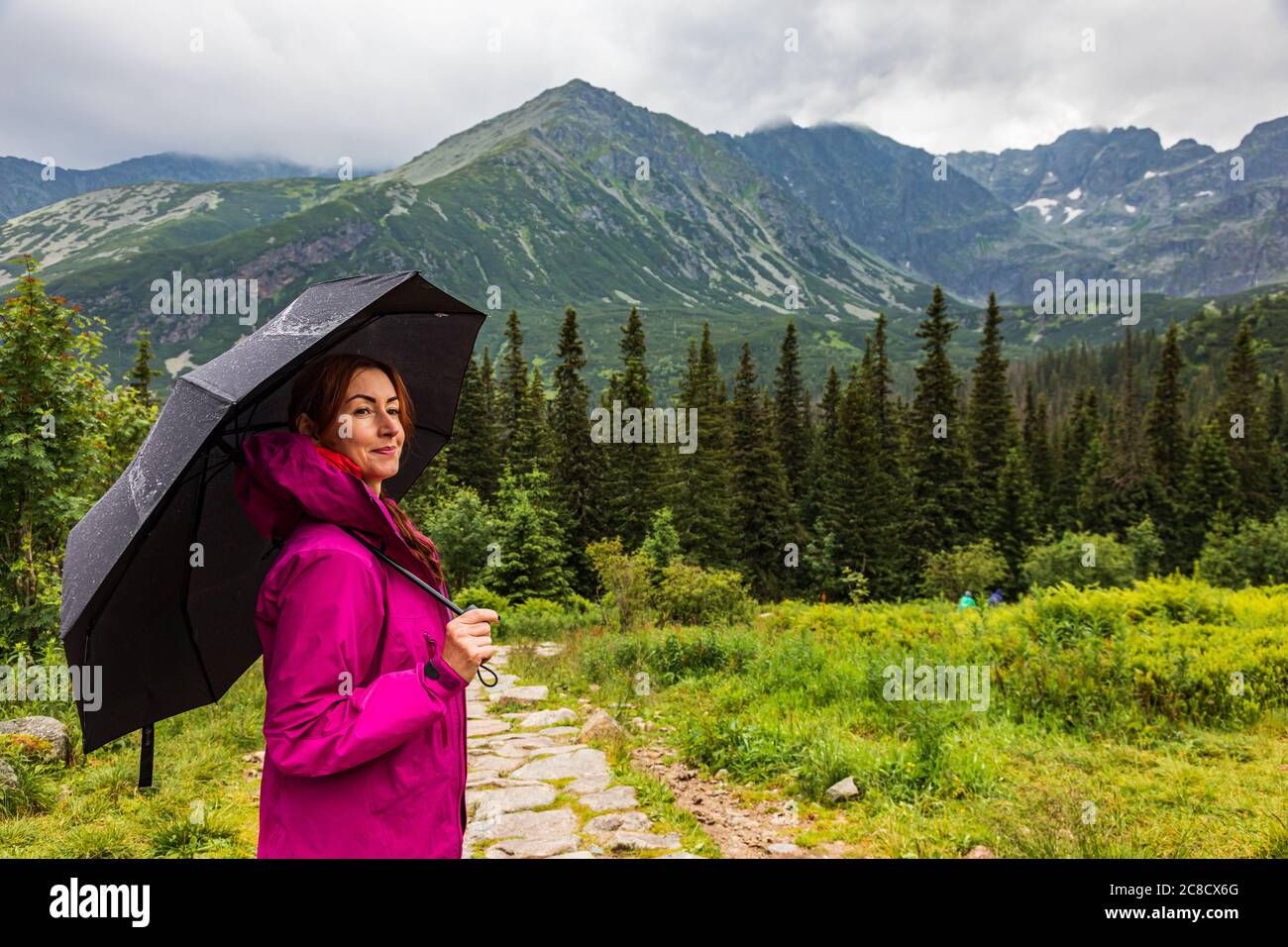 Beautiful mature woman with the umbrella in the mountain scenery Stock Photo