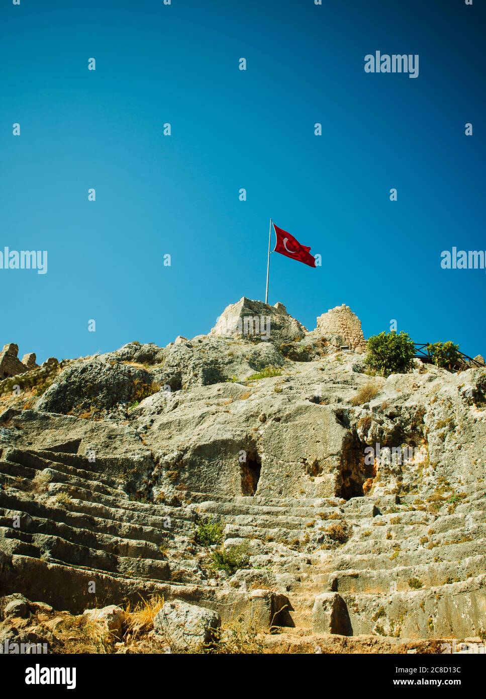 Turkish flag flying on top of the Byzantine castle in the town of Kaleköy on the Mediterranean sea, Turkey Stock Photo