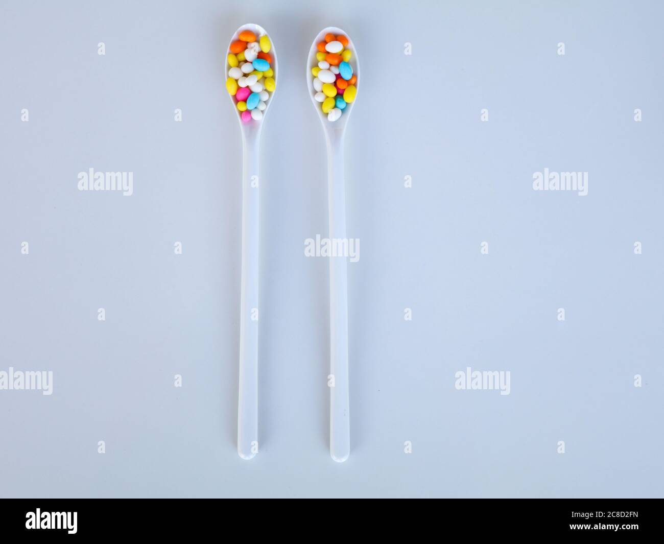 Multi colored sweet fennel sugar candy in white spoons against white