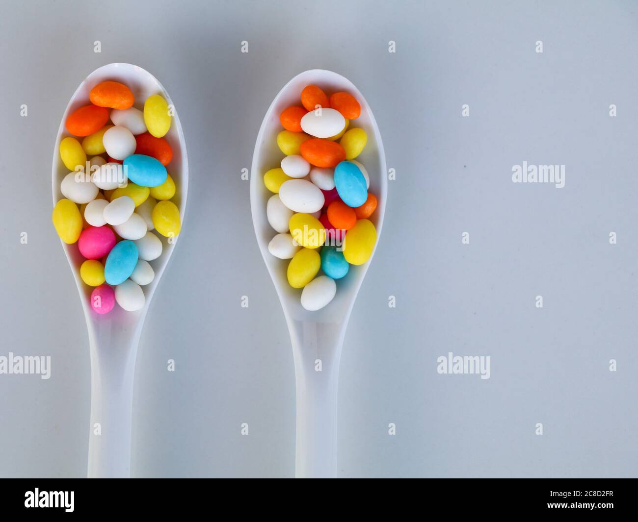 Multi colored sweet fennel sugar candy in white spoons against white