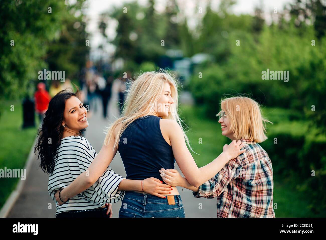 Back view of three beautiful women sitting on grass and hugs Stock ...