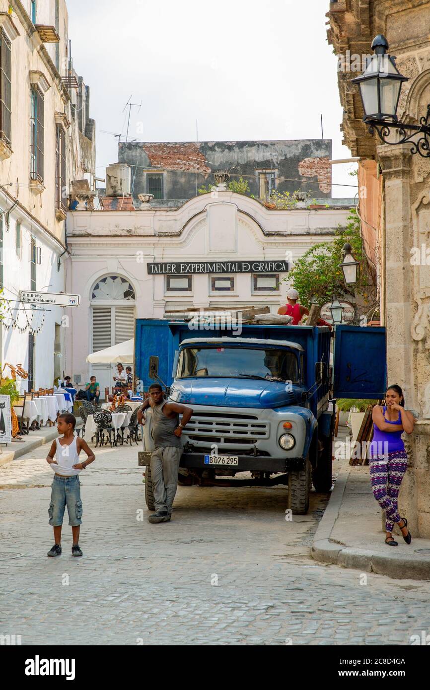 Havana / Cuba - 04.16.2015: Local Cuban men and woman standing on the street in front of an old blue truck Stock Photo