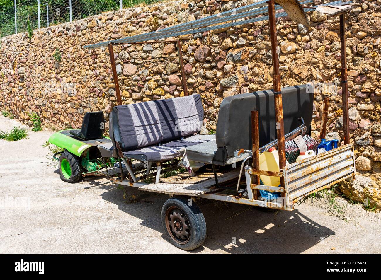 Old green tractor adapted with a trailer to carry passengers and garden