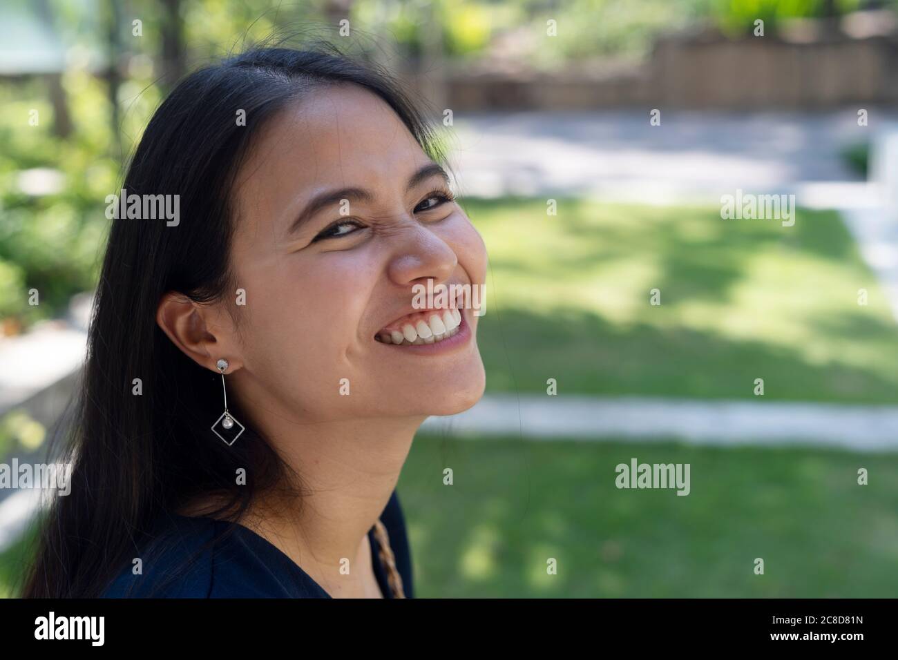 Close up shot of long hair woman smile the camera while sitting in the park. Stock Photo