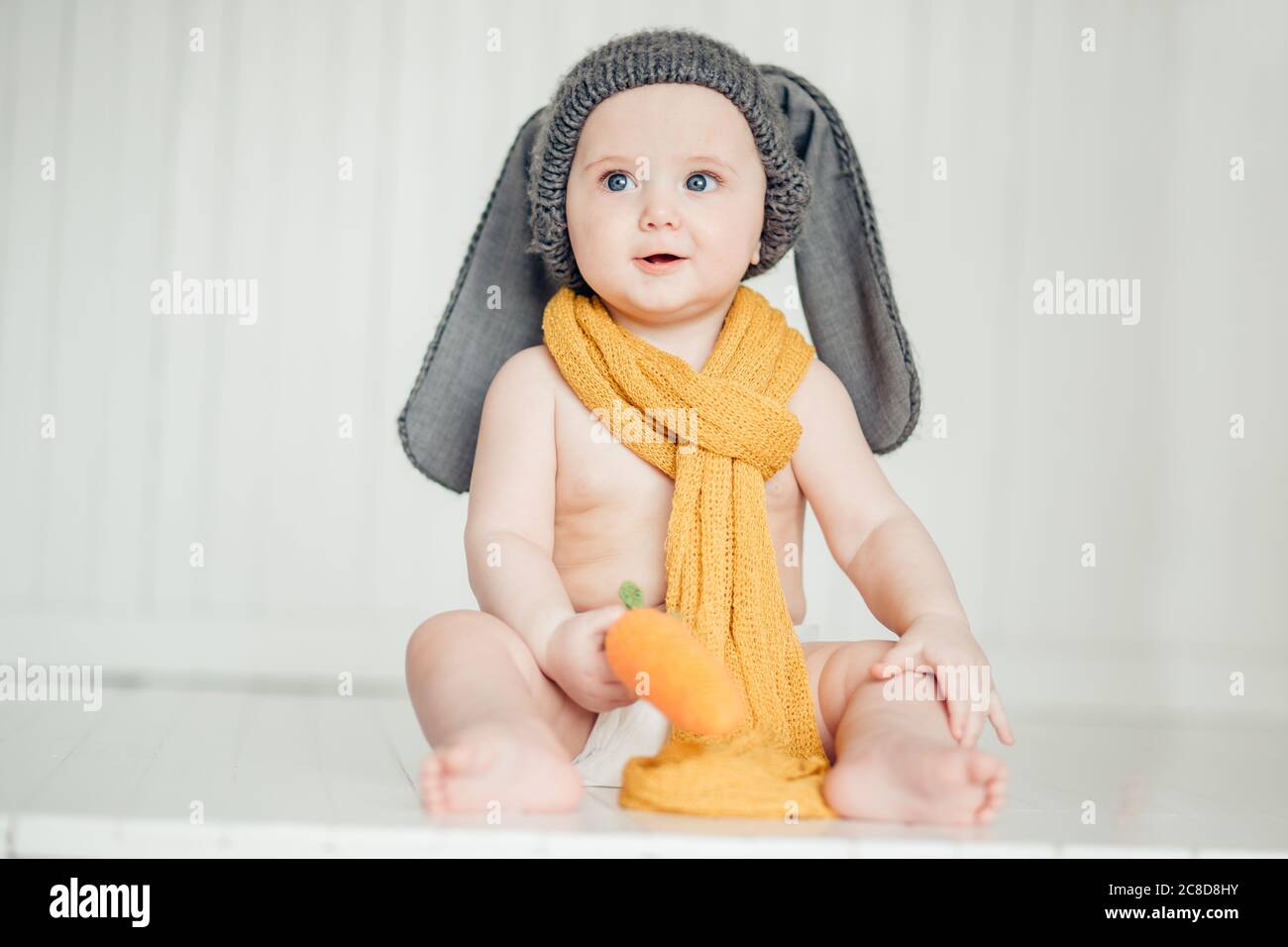 childhood, babyhood and people concept - happy little baby boy or girl sitting on floor at home Stock Photo