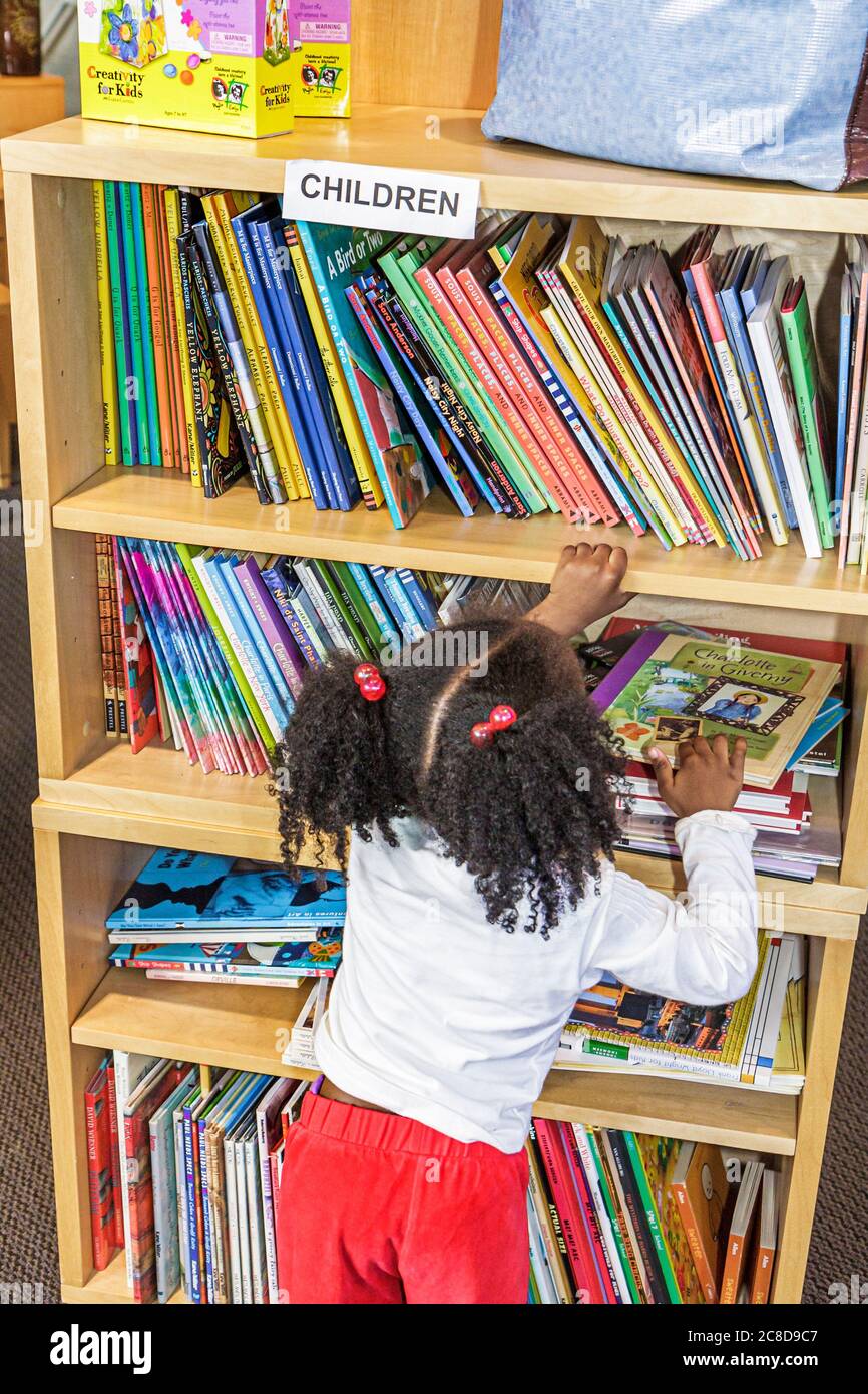 Jacksonville Florida,MOCA,Museum of Contemporary Art gift shop,children's books Black girl child preschooler bookshelf reaching,inside interior Stock Photo