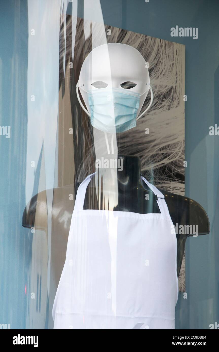 Sinister masked mannequin wearing PPE (personal protection equipment), in the window of a hairdressers salon, during the Coronavirus pandemic. England. Stock Photo