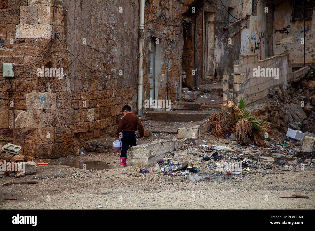 A scene from the back street slums of Tartus, Syria. It is a rundown dirty neighborhood with ruble and trash on the abandoned streets and ruined house Stock Photo