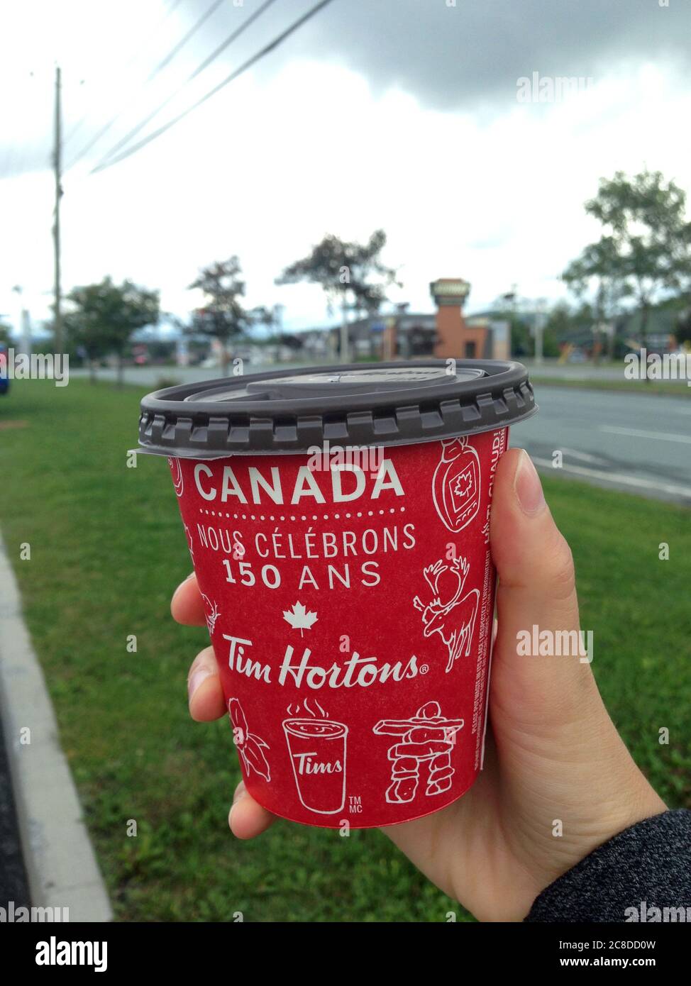 Quebec, Canada - 20 August 2017: Tom Hortons' coffee-to-go cup with 150th anniversary of Canada theme. Stock Photo