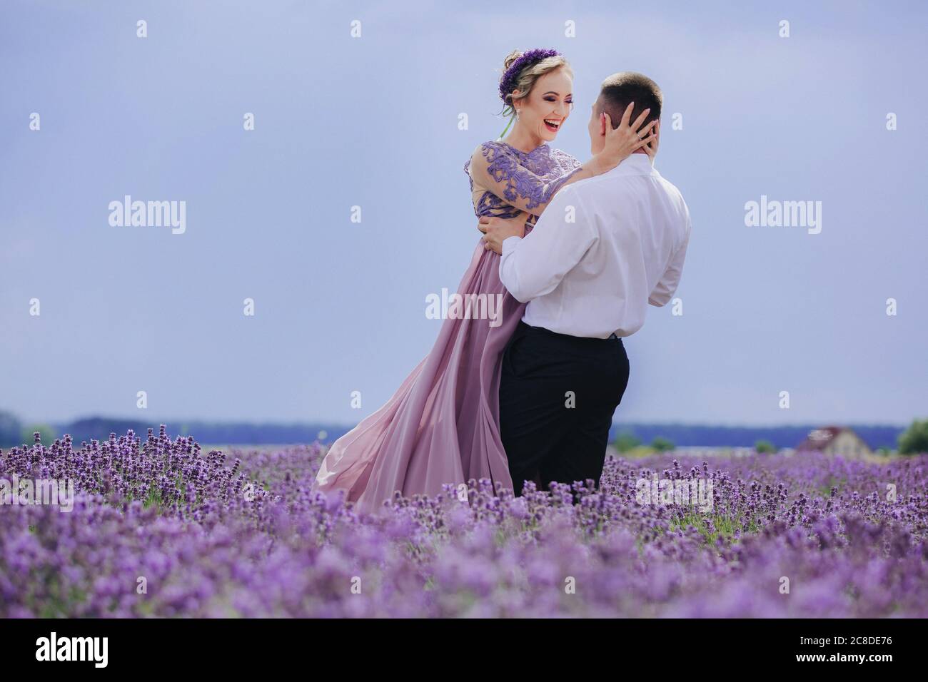 Young couple in love hugging and walking in a lavender field on summer  cloudy day. girl in a luxurious purple dress and with hairstyle Stock Photo  - Alamy