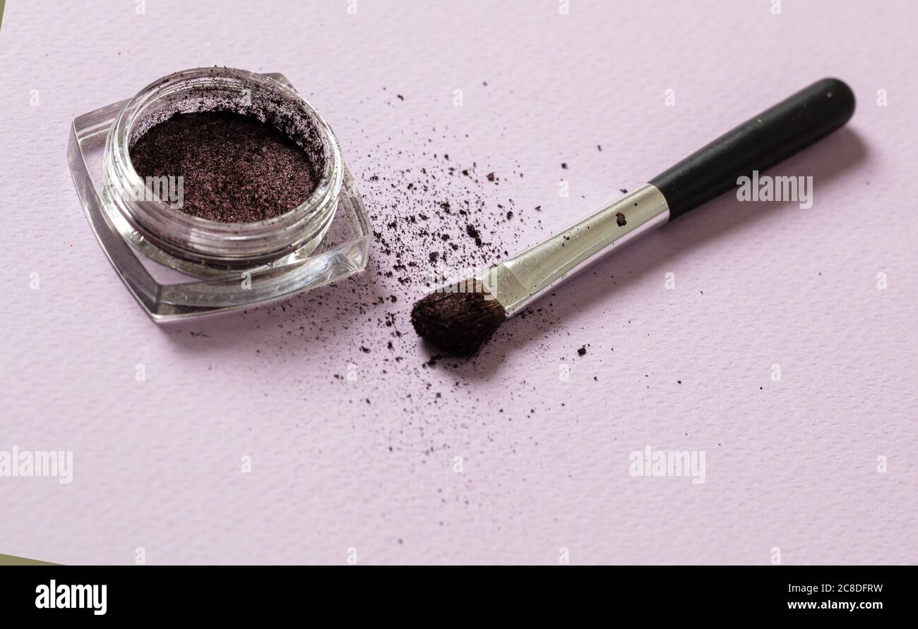 Eyeshadow purple color and brush against pink background, closeup view. Professional tools for make up, beauty salon, cosmetics concept Stock Photo