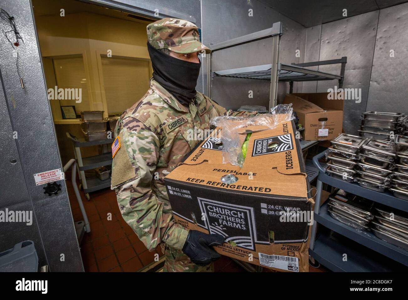 U.S. Army Pfc. Raul Cabrera, Culinary Specialist, Foxtrot Company, 250th Brigade Support Battalion, New Jersey Army National Guard, carries a box of lettuce in to a refrigerated storage room at Veterans Haven North, Glen Gardner, N.J., April 30, 2020. Five New Jersey National Guard Soldiers and three Airmen are assisting the kitchen staff, which is responsible for preparing 2,400 meals a day for both the Haven’s residents, as well as the residents at the Hunterdon Developmental Center. Veterans Haven North, which is operated by the New Jersey Department of Military and Veterans Affairs, is a t Stock Photo