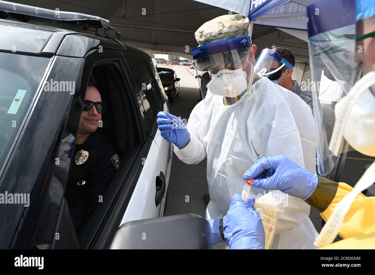 Lt. Col. Dwight Harley, of the 119th Medical Group, takes a swab sample from an asymptomatic Fargo police officer who is volunteering to take a COVID-19 test in the parking lot of the FaroDome, N.D., April 25, 2020. He is wearing personal protective equipment (PPE) to stay safe while he works and help prevent the spread of the Coronavirus while testing people as they drive through the mass testing process in their vehicles. He is just one of the many N.D. National Guard members partnering with the N.D. Department of Health and other civilian agencies in support of the whole community response Stock Photo