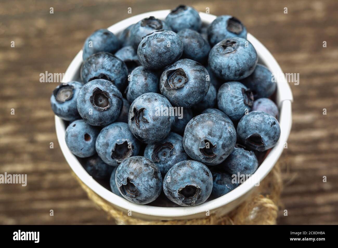 Some blueberries in a decorate small bucket on wooden banch in the garden on summer sunset, close up shot, healthy food concept Stock Photo