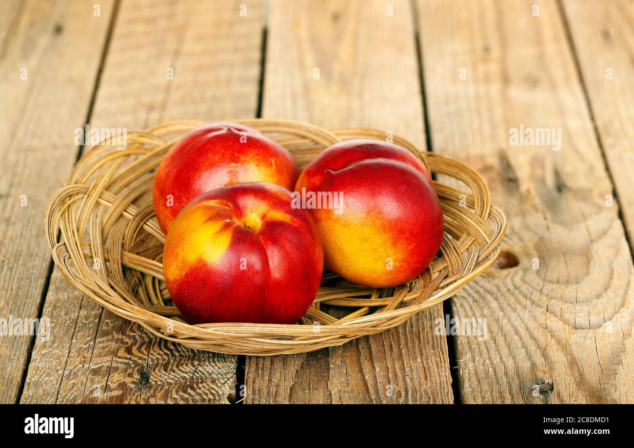 basket with nectarines on wooden surface Stock Photo