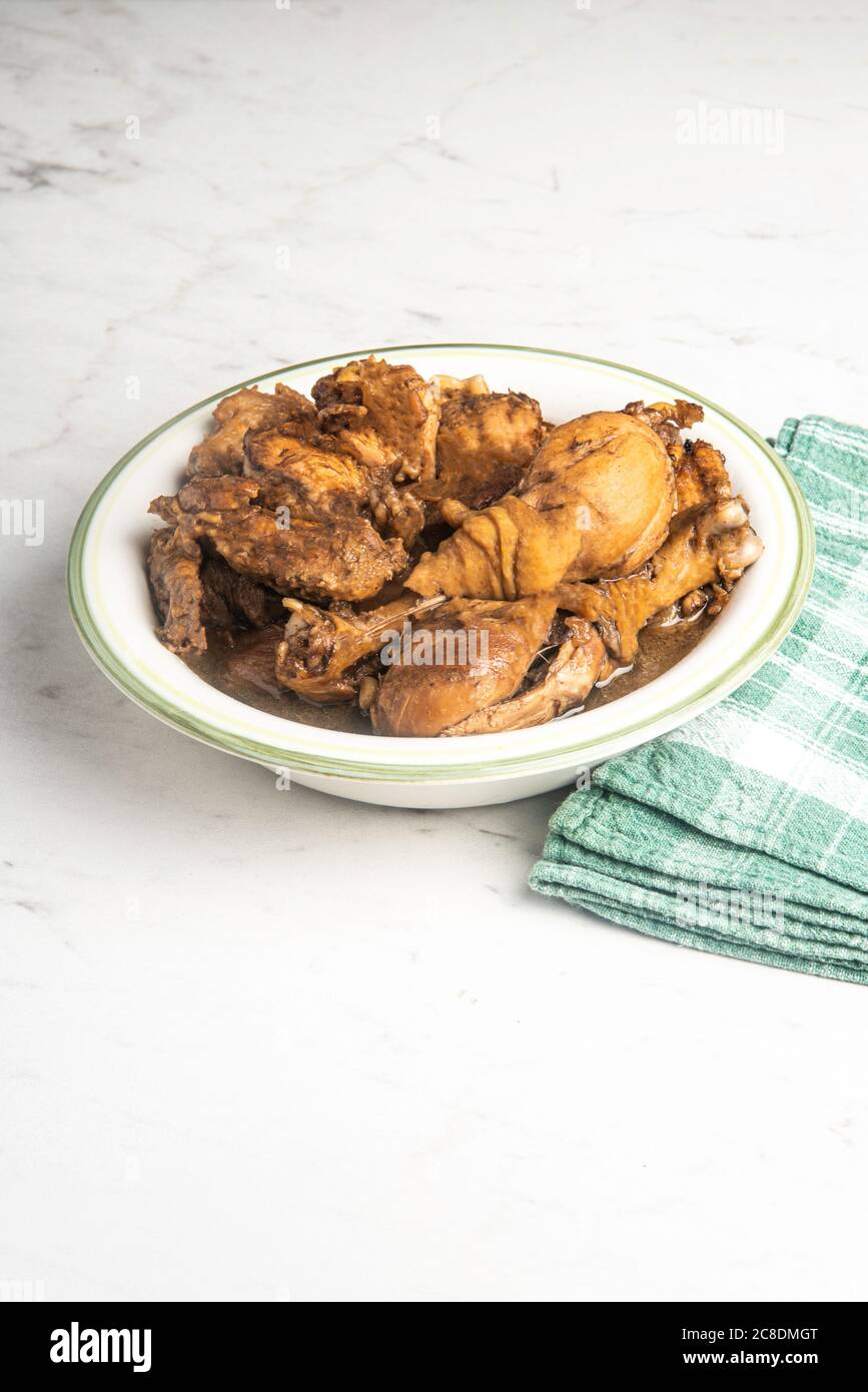 A serving of Filipinostyle chicken adobo dish in a bowl with a green