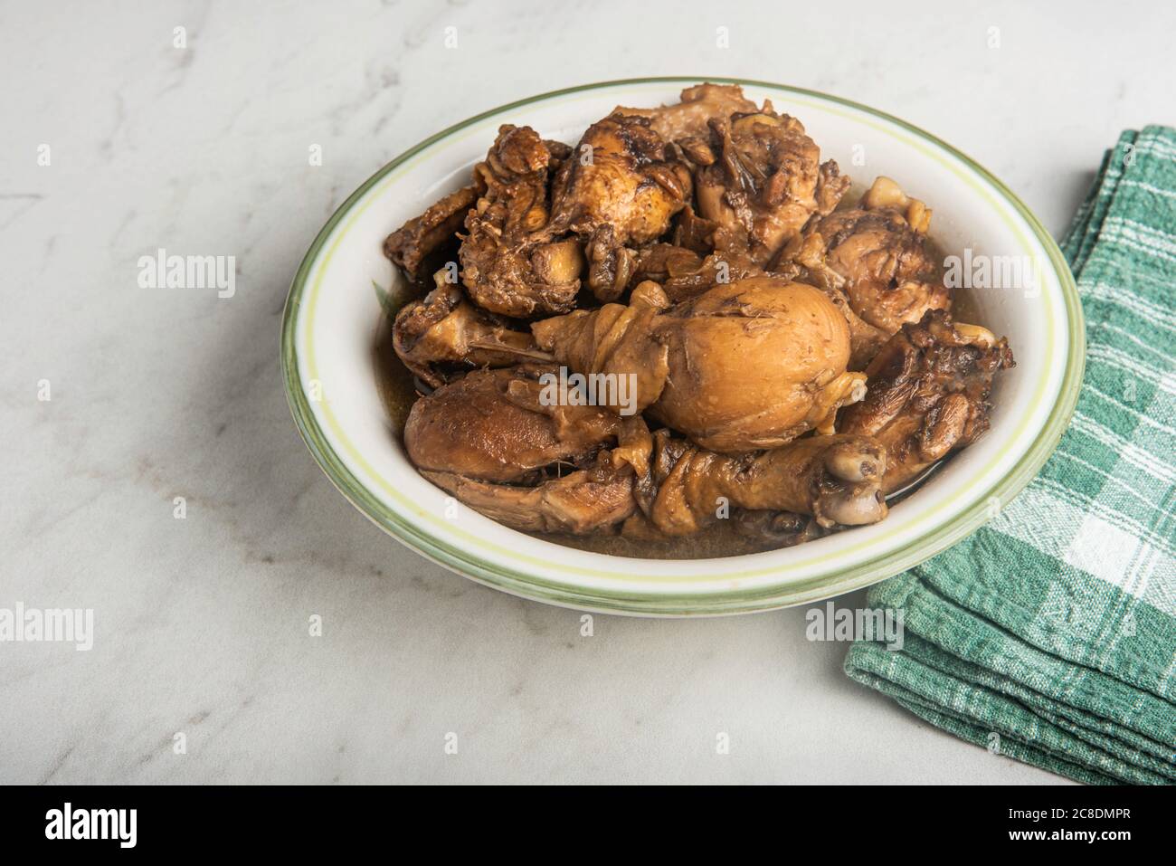 A serving of Filipinostyle chicken adobo dish in a bowl with green