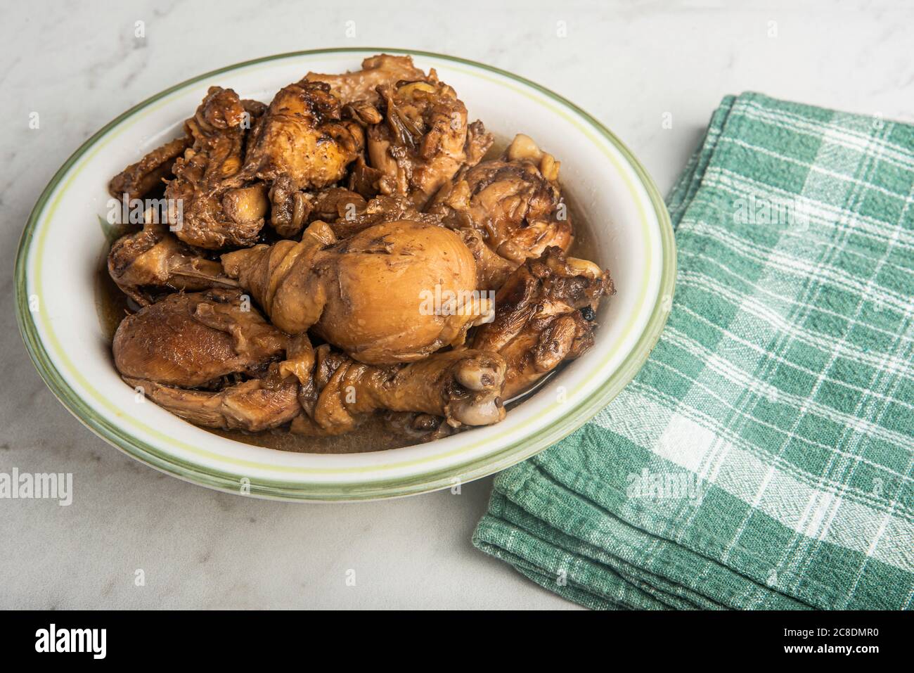 A serving of Filipinostyle chicken adobo dish in a bowl with green