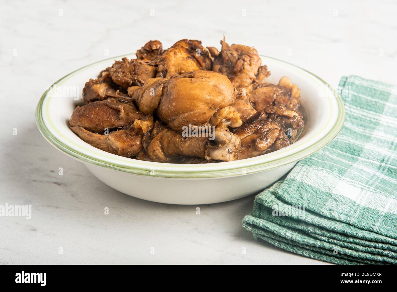 A serving of Filipinostyle chicken adobo dish in a bowl with green