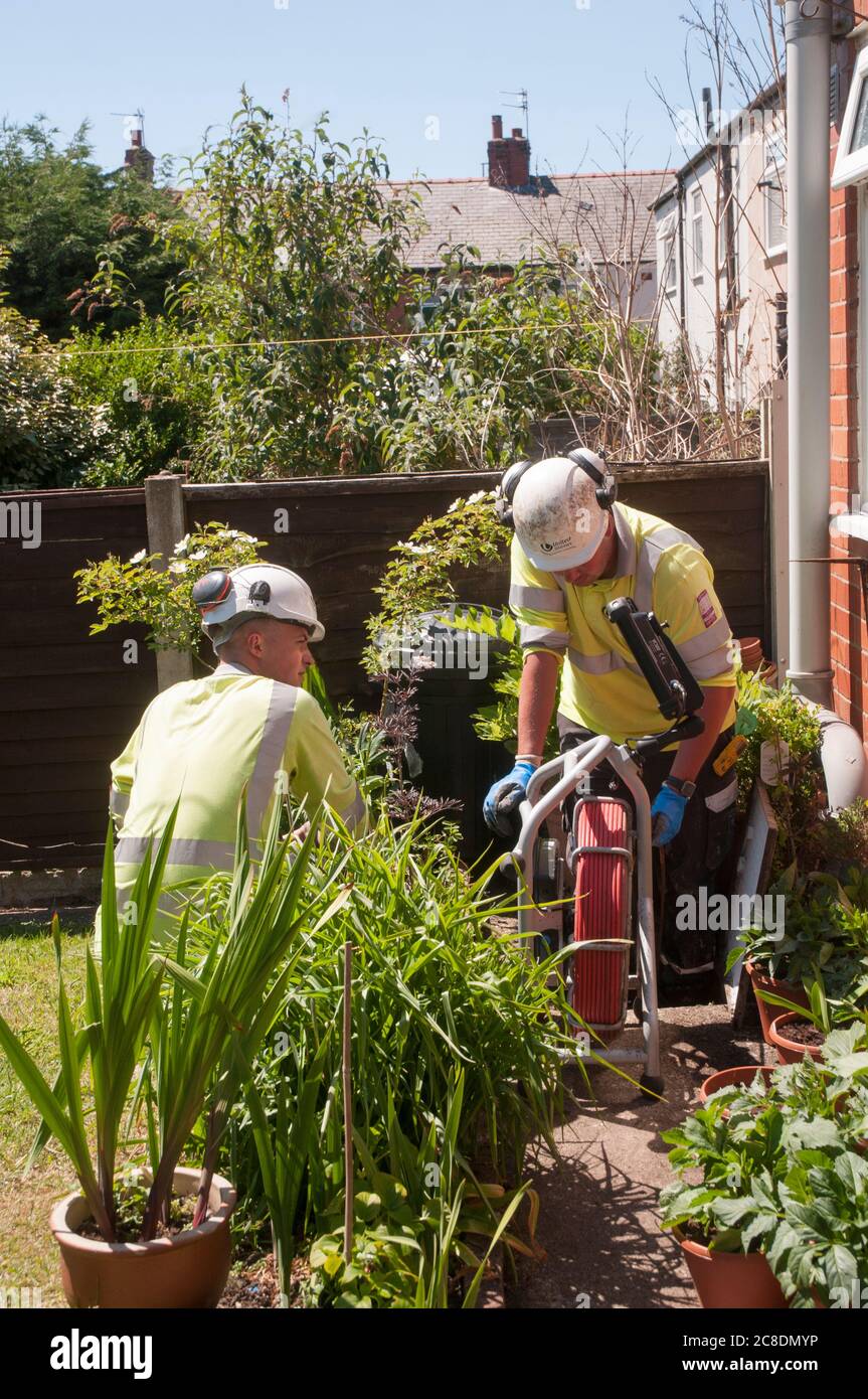 Workmen using a camera and screen to inspect and map drains at rear of a house Stock Photo