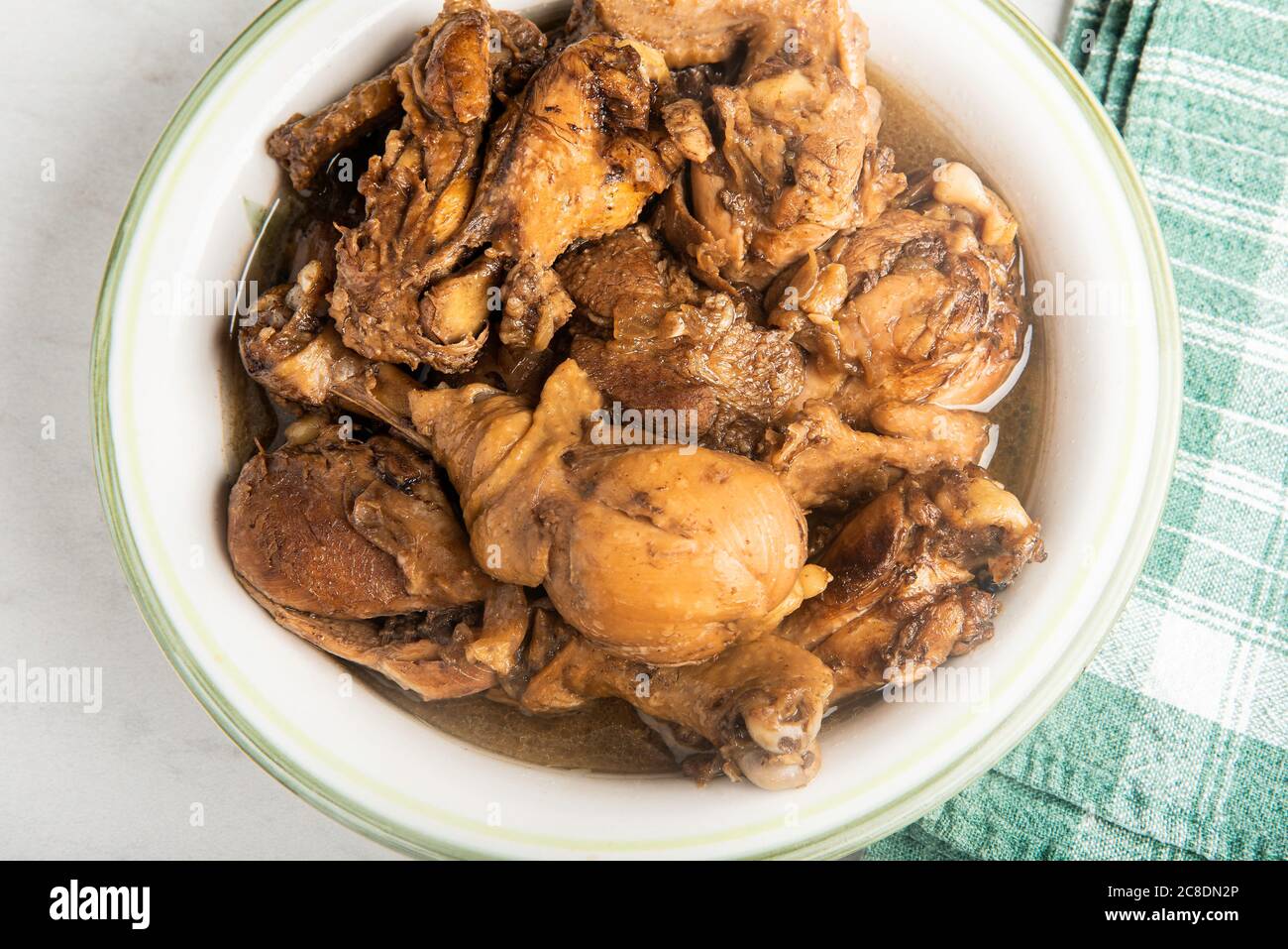 A serving of Filipinostyle chicken adobo dish in a bowl with green