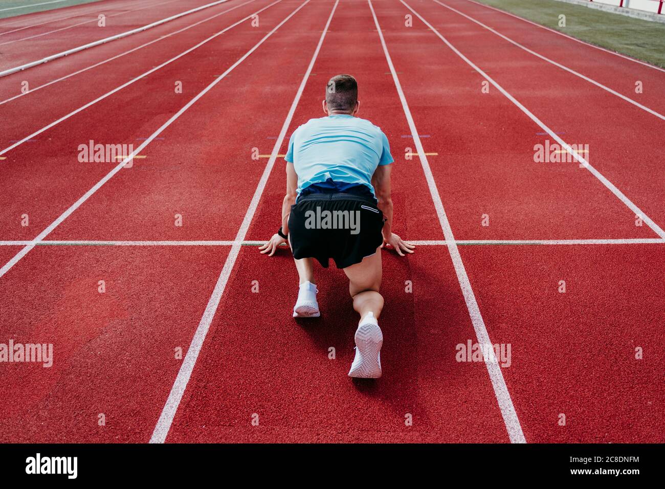 Male athlete in starting position on tartan track Stock Photo