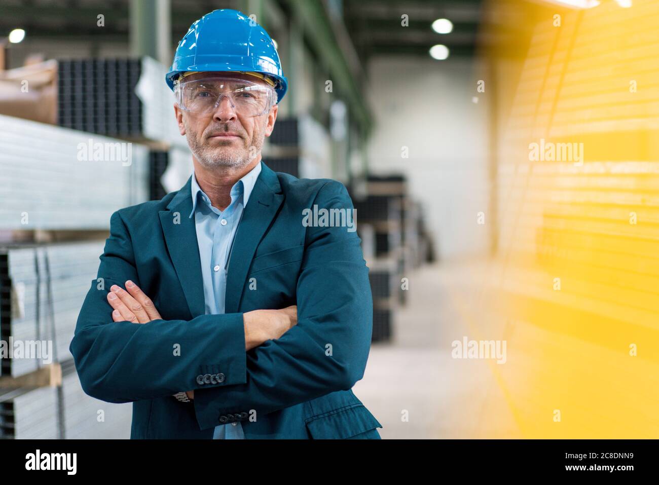 Portrait of mature businessman wearing hard hat and safety goggles in a factory Stock Photo