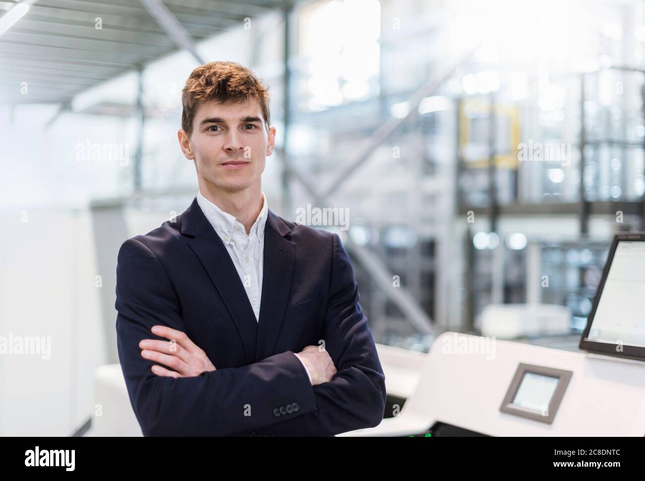 Confident businessman with arms crossed standing in factory Stock Photo ...