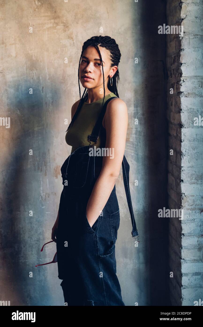 Portrait of a stylish young woman standing at a wall Stock Photo - Alamy